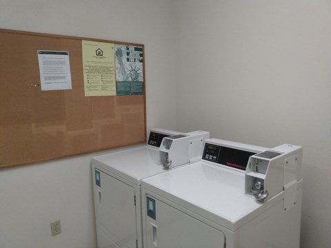 A white cabinet with a brown board on the wall above it.