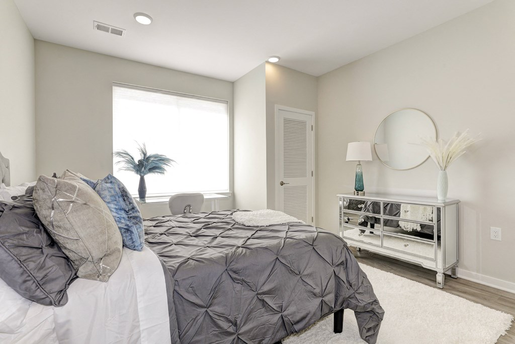 a bedroom with a large bed and a dresser with a mirror