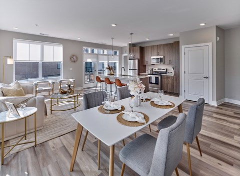 A modern dining room with a white table and grey chairs.