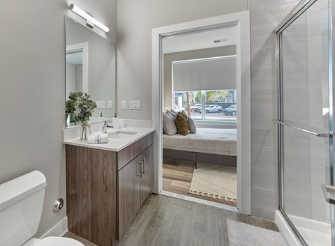 A bathroom with a white toilet, a sink with a mirror above it, and a glass shower door.