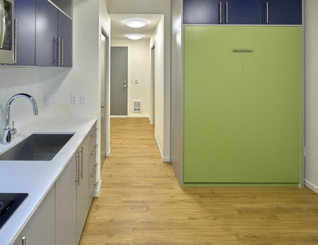 a long hallway with a green refrigerator in a kitchen