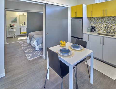 a kitchen and dining area with a table and chairs and a bedroom