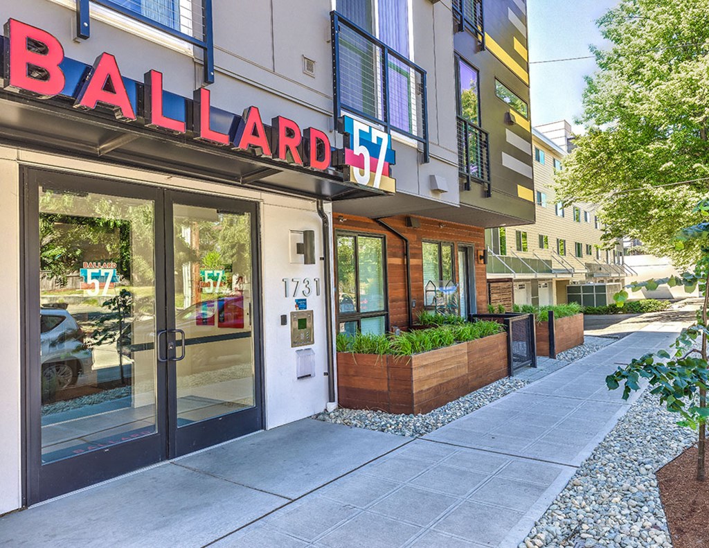 a sidewalk in front of a building with a ballard sign