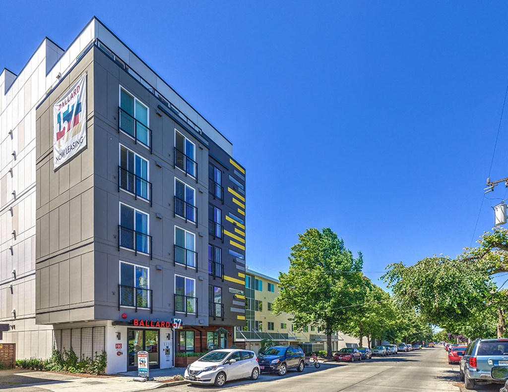 a city street with cars parked in front of a tall building