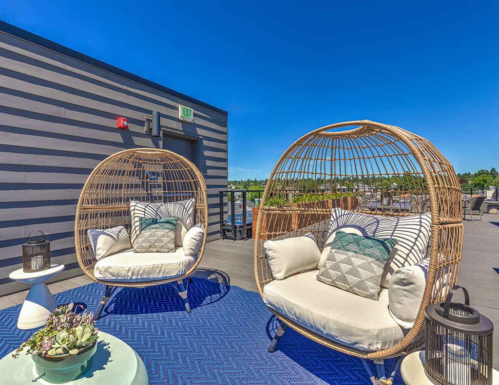 a porch with two chairs and a table with pillows