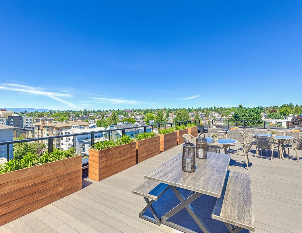 a rooftop terrace with tables and chairs and a view of the city