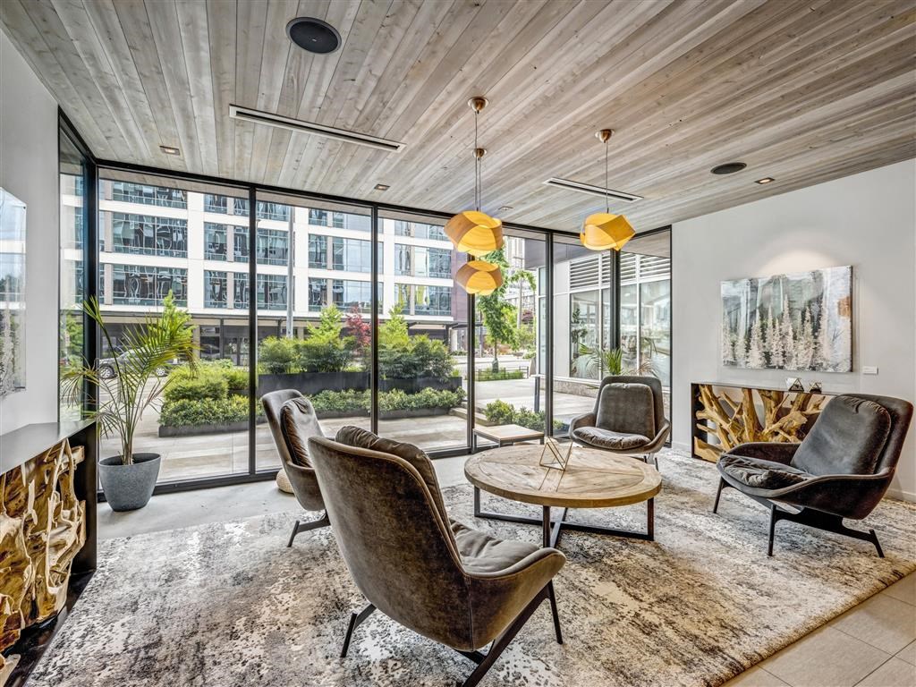 a living room with chairs and a table and large windows
