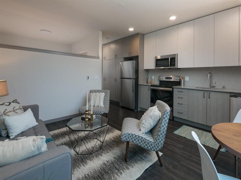 a living room with a couch and chairs and a kitchen