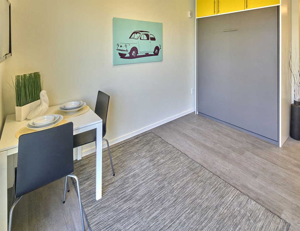 a dining room with a table and a painting of a car on the wall