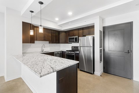 a kitchen with a marble counter top and stainless steel refrigerator