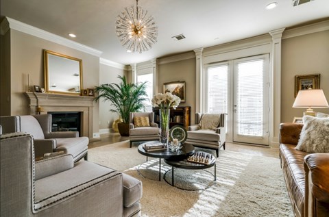 A living room with a grey couch, a coffee table, a fireplace, and a chandelier.
