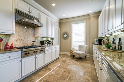 A kitchen with white cabinets and a beige floor.