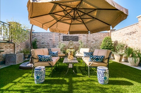 A patio with a table, chairs, and a large umbrella.