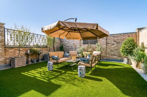 A patio with a couch and umbrella.