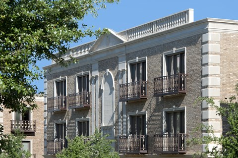 A building with a balcony and a tree in front of it.