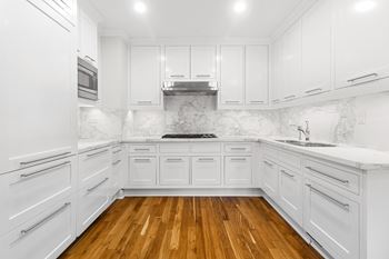 a white kitchen with white cabinets and a wood floor at HIGHGROVE, Stamford, Connecticut