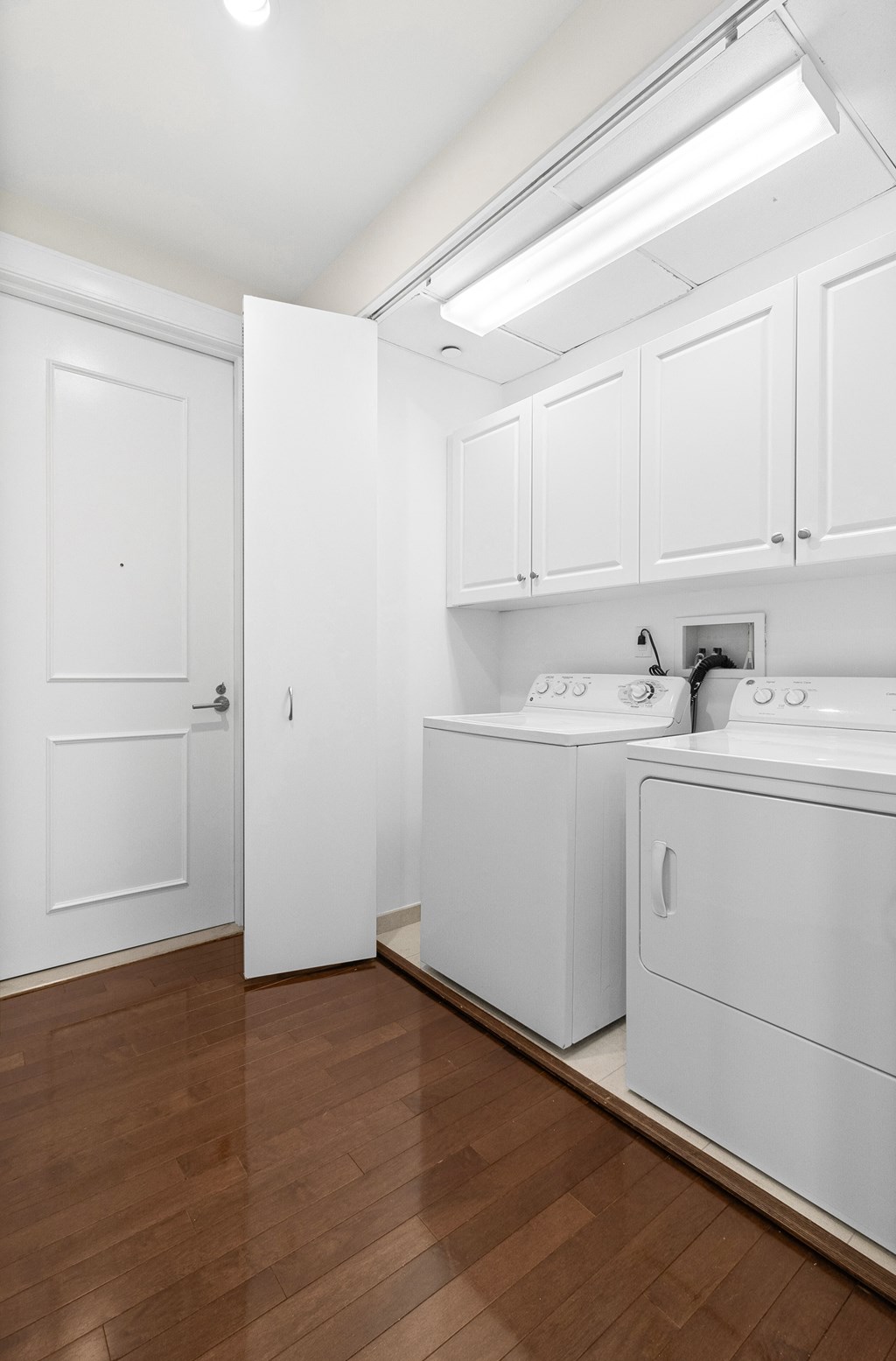 a washer and dryer in a room with white cabinets and a wood floor at HIGHGROVE, Stamford, CT