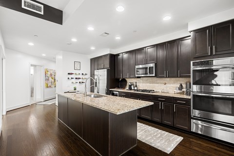A modern kitchen with dark wood cabinets and stainless steel appliances.