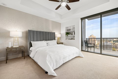 A bedroom with a large bed and a balcony overlooking the city.