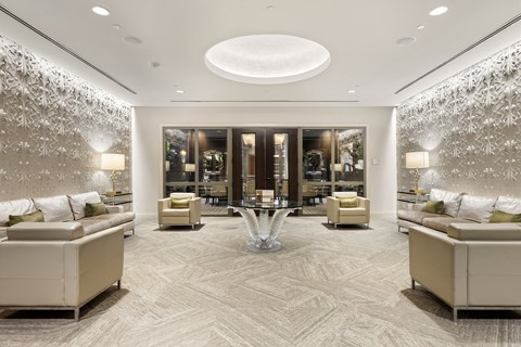 A spacious living room with a patterned carpet and a large circular ceiling light.