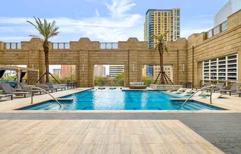 A pool surrounded by a wooden deck and palm trees.