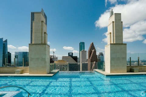 A swimming pool with two pillars in the middle and a city skyline in the background.