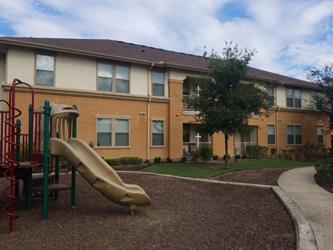A playground with a slide in front of a building.