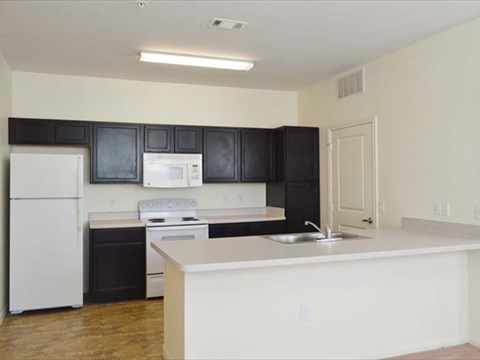 A kitchen with black cabinets and white appliances.