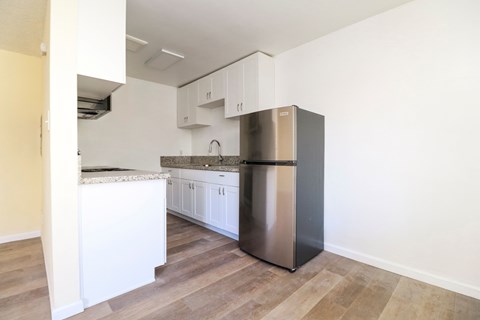 A kitchen with a stainless steel refrigerator and white cabinets.