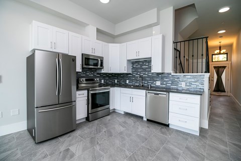 A modern kitchen with a stainless steel refrigerator and white cabinets.