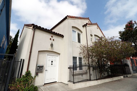 A white house with a black gate and a brown roof.