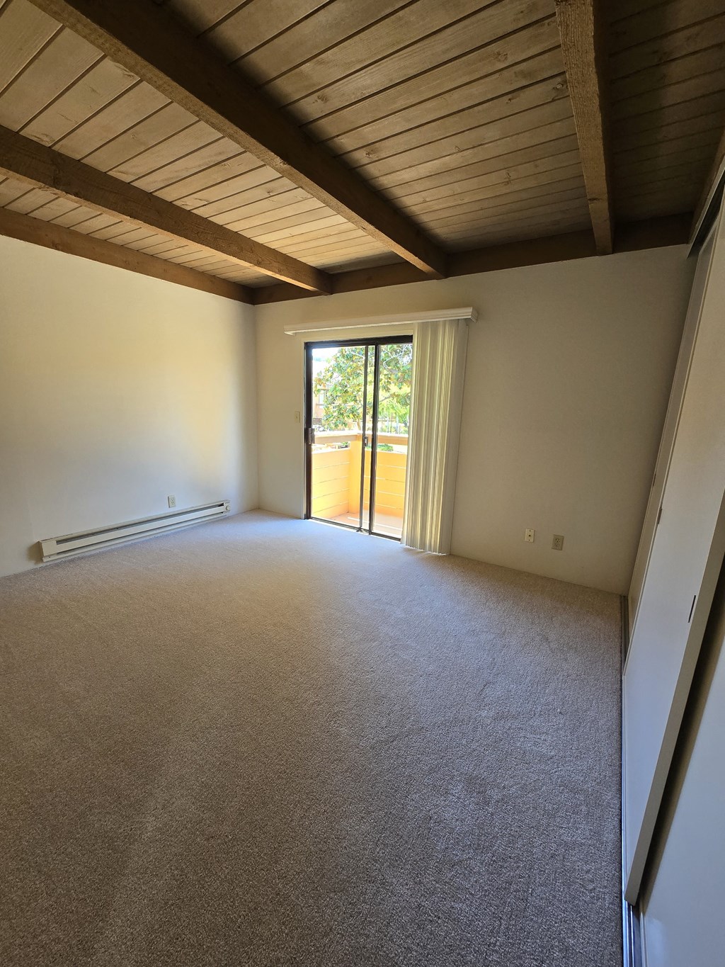 an empty living room with a sliding glass door to a patio