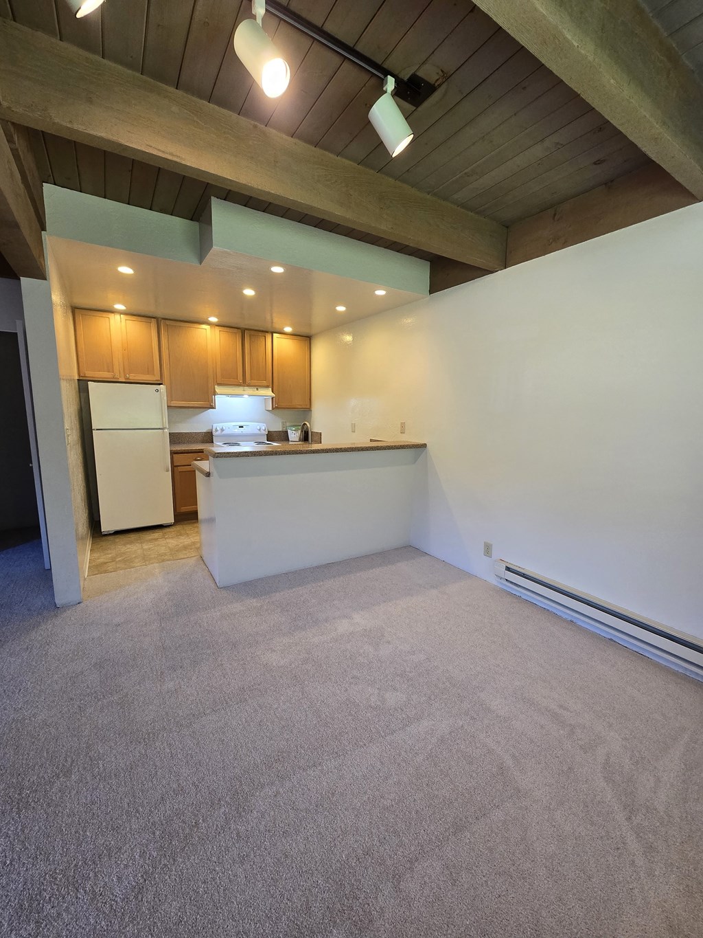 the living room and kitchen of an empty house with a carpeted floor