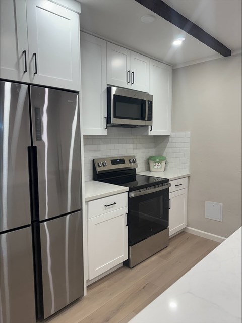 A modern kitchen with a stainless steel refrigerator, microwave, and oven.