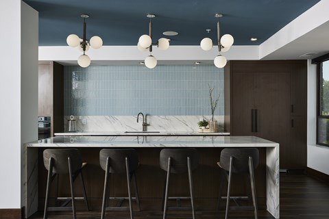 A modern kitchen with a marble countertop and bar stools.