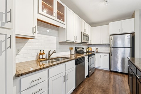 A kitchen with white cabinets and a granite counter top.