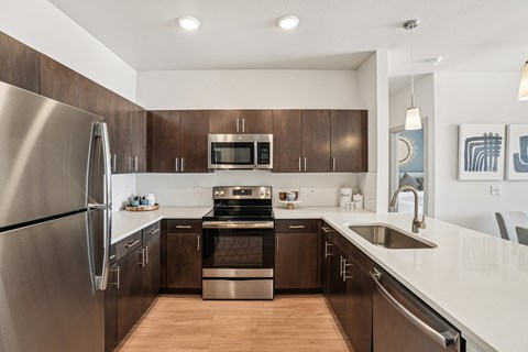 A modern kitchen with dark wood cabinets and stainless steel appliances.