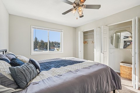 A bedroom with a large bed and a ceiling fan.