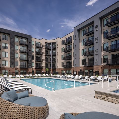 an outdoor pool with lounge chairs at an apartment building