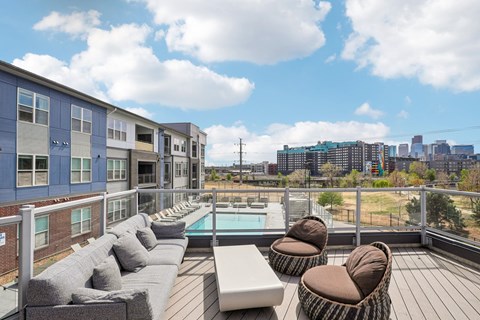 A patio with a pool and chairs overlooks a city skyline.