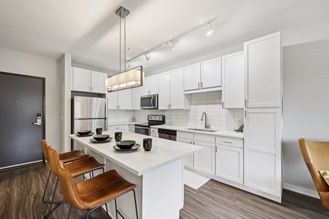 A modern kitchen with white cabinets and a wooden table.
