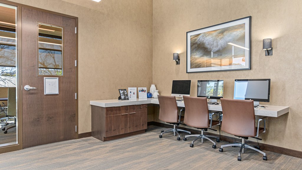 a conference room with four computers and a desk with chairs