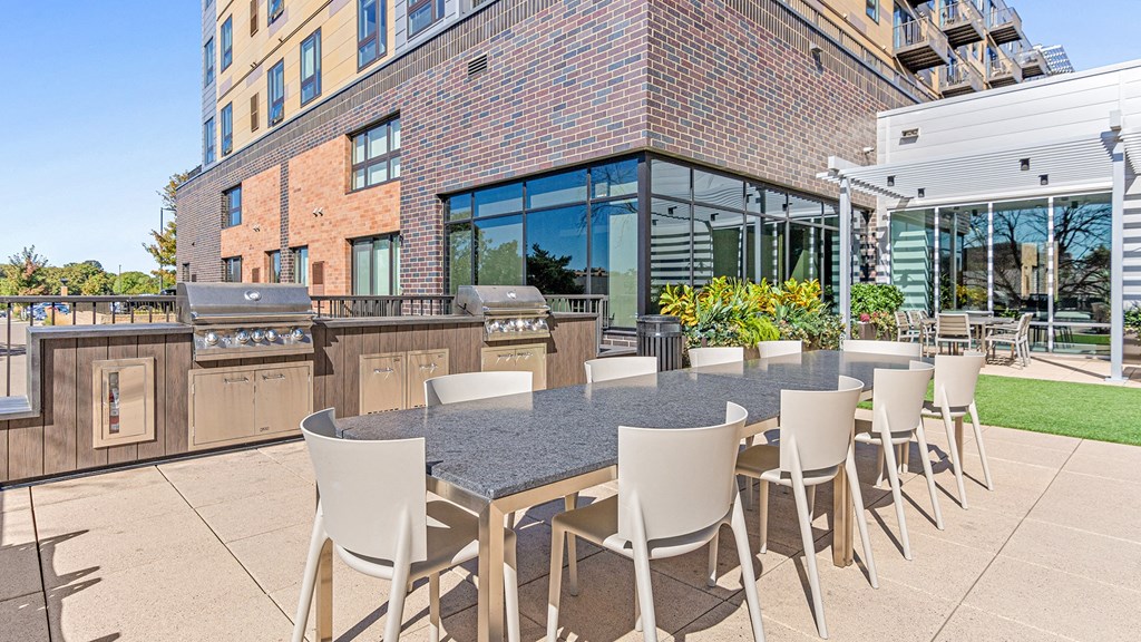 a patio with a table and chairs and a barbecue grill