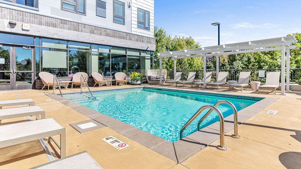 a swimming pool with lounge chairs and a building with glass windows