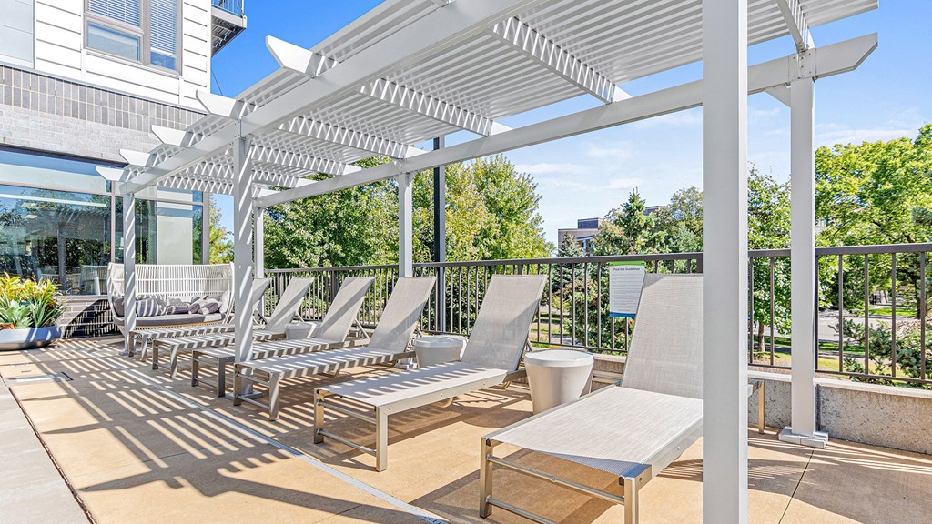 a patio with lounge chairs and tables and a white canopy