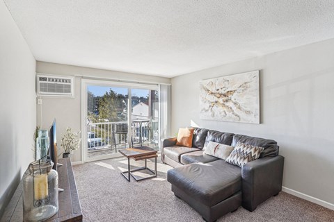 A living room with a grey couch and a painting on the wall.