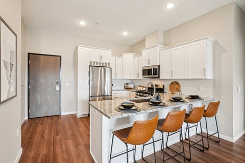 A kitchen with a white counter top and brown chairs.