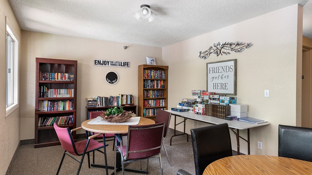 a library with a table and chairs and a bookcase filled with books