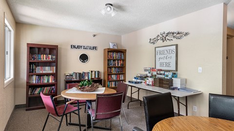 a library with a table and chairs and a bookcase filled with books