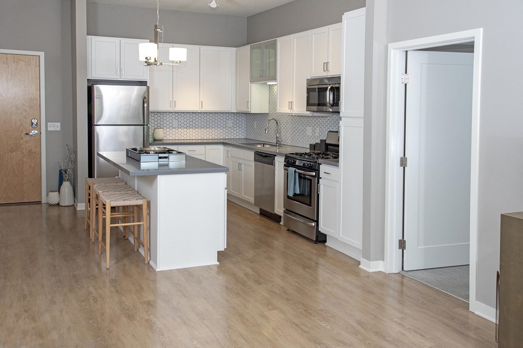 Kitchen with white cabinetry filled with natural light and faux light wood floors throughout.